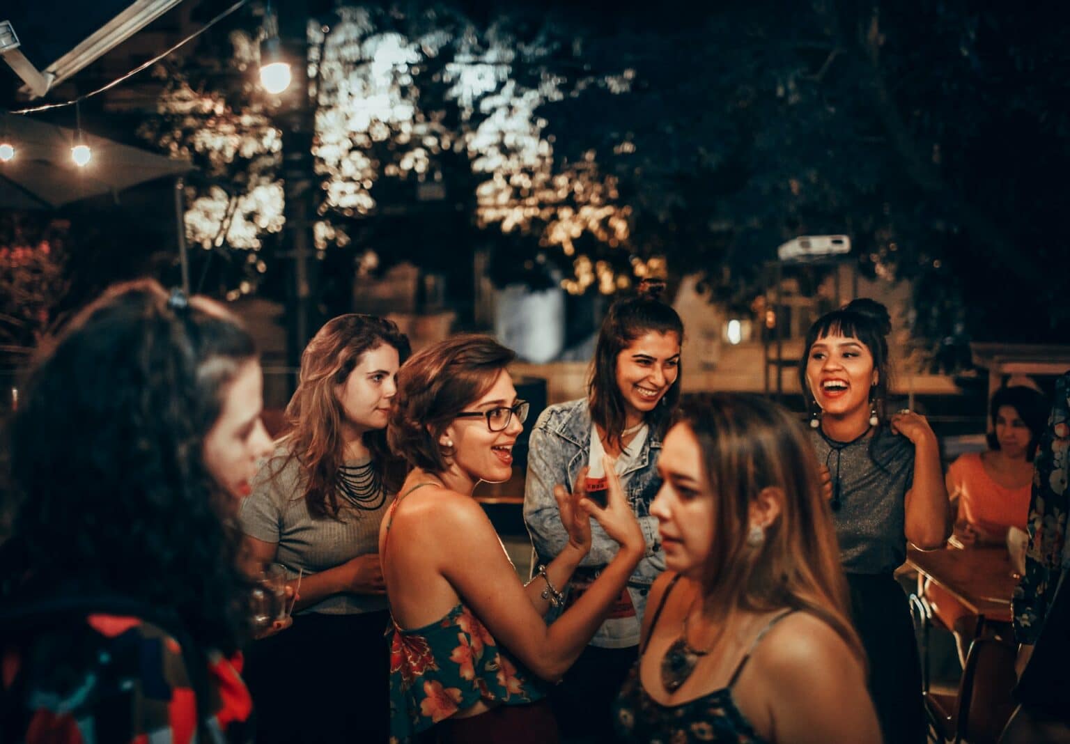 Gruppe von Gästen unterhält sich und lacht bei einer sommerlichen Abendveranstaltung im Freien.