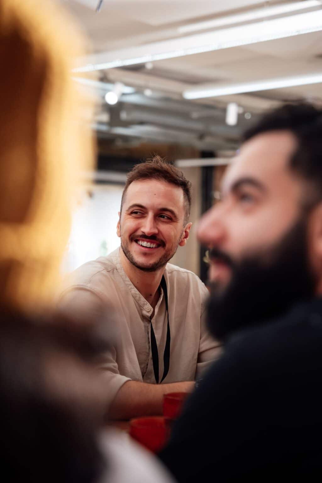Lächelnder Teilnehmer im Gespräch während eines Business-Meetings in moderner Arbeitsumgebung.