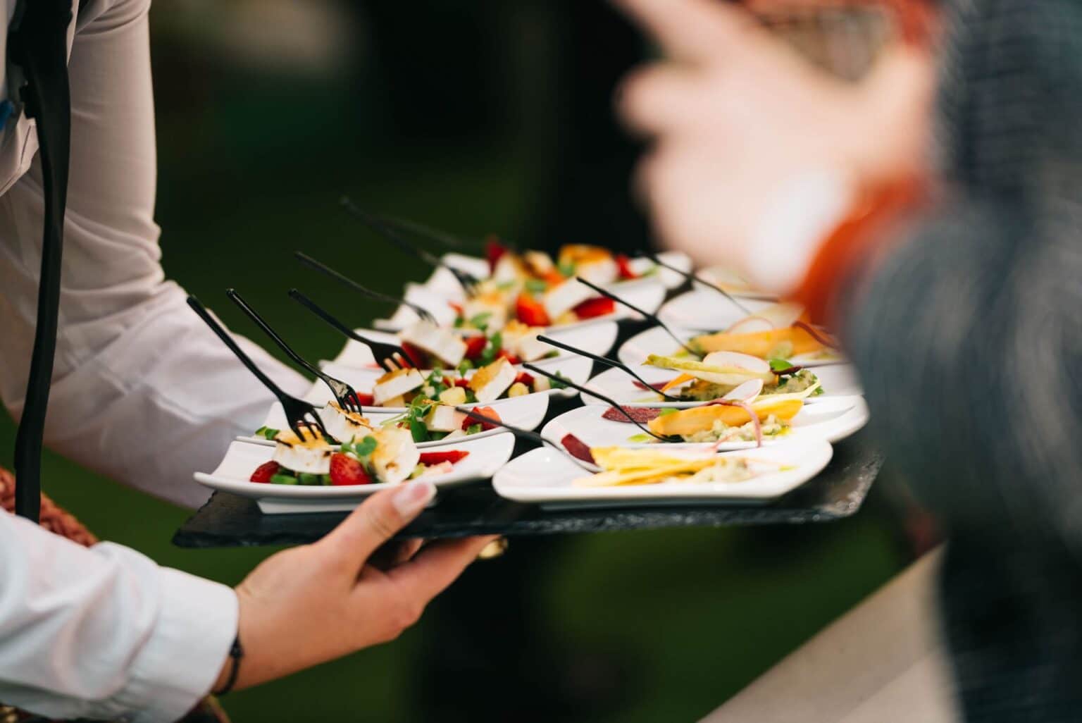 Servicekraft serviert hochwertiges Fingerfood bei einer Firmenveranstaltung oder einem Empfang.