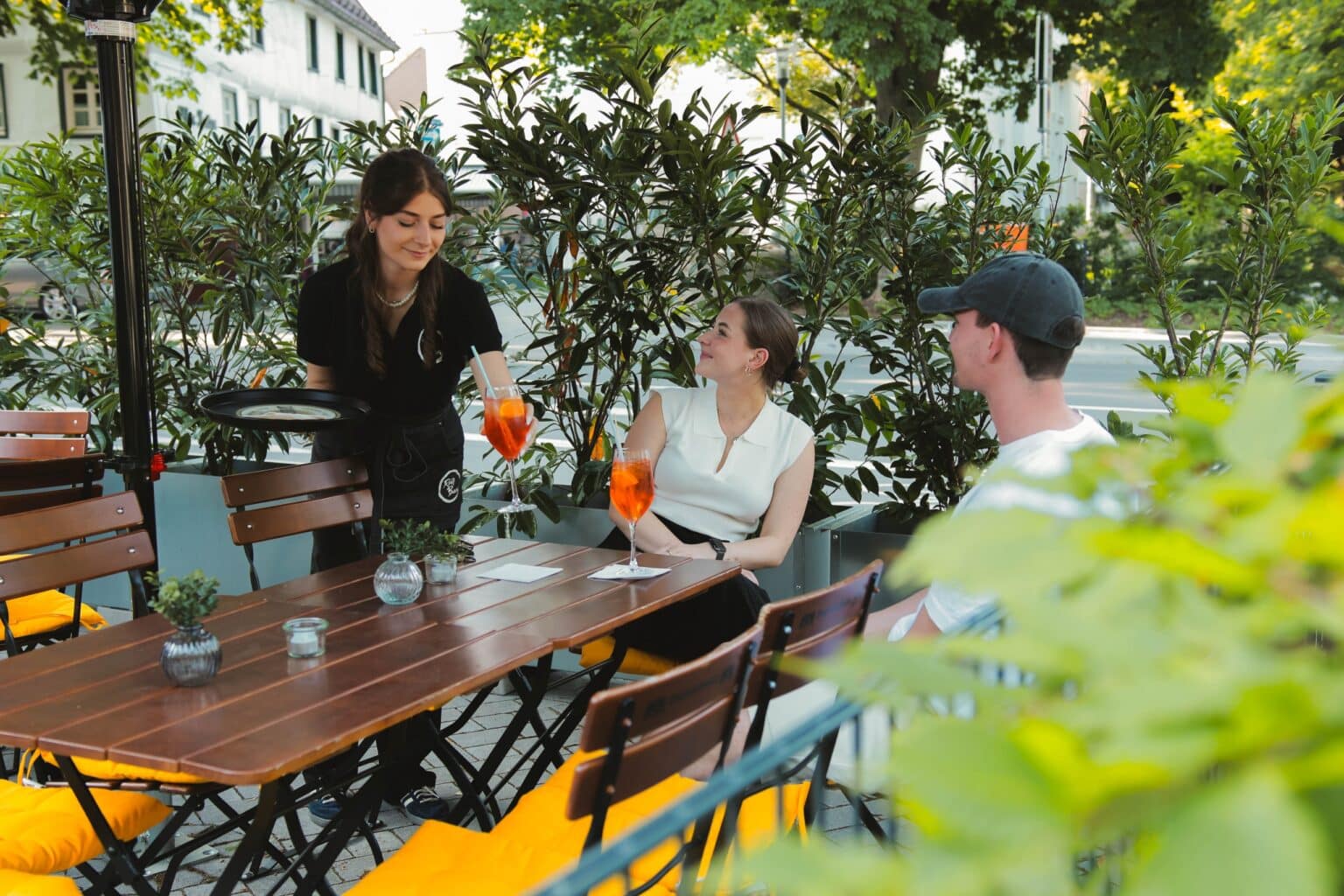 Servicekraft bedient Gäste im gemütlichen Biergarten des Morgentors in Unna.