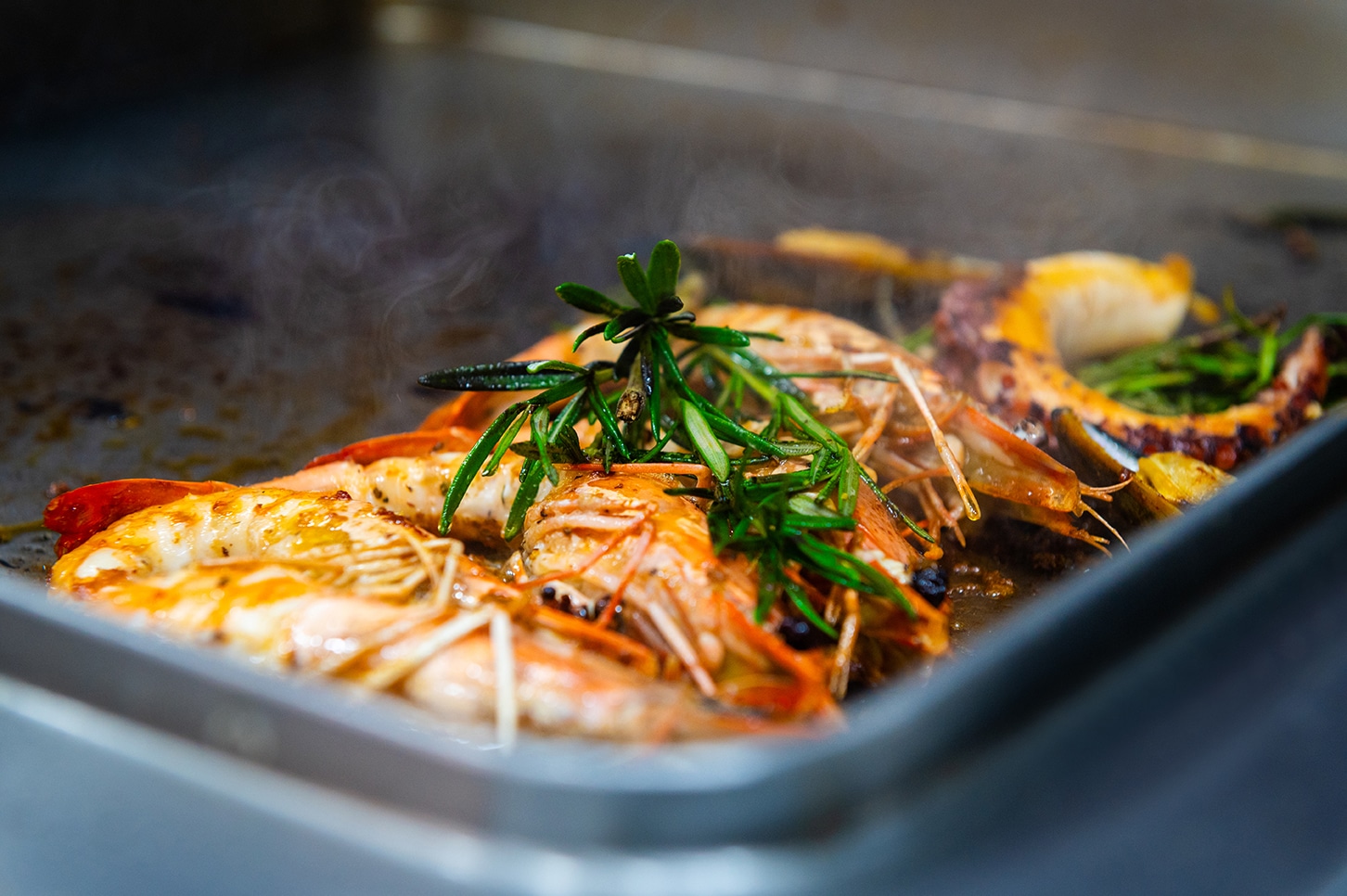 Frische Garnelen mit Rosmarin auf der Grillplatte in der offenen Küche der Neuen Schmiede in Unna.