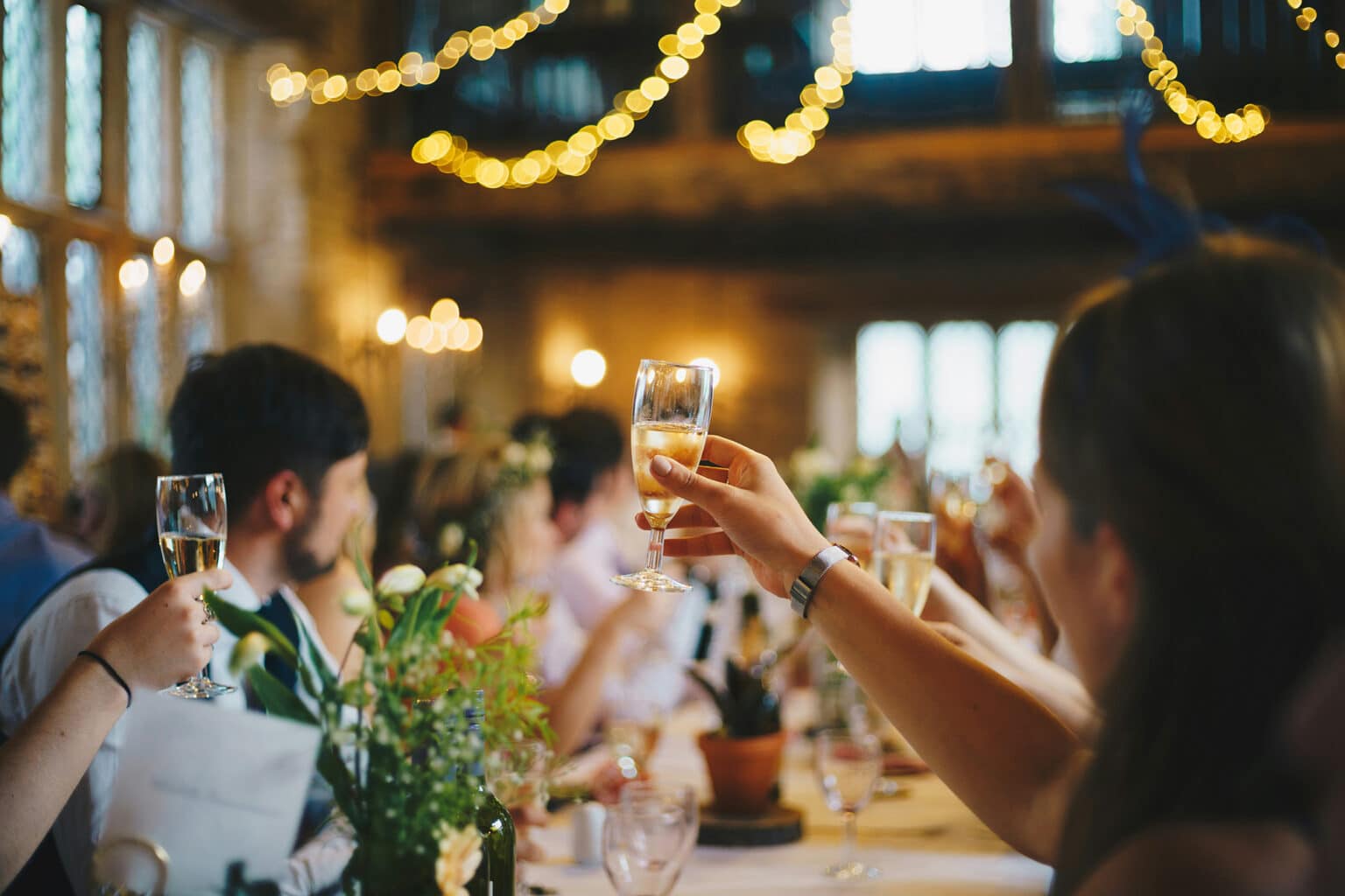 Gäste stoßen bei einer Hochzeitsfeier in einer stilvoll dekorierten Eventlocation mit Sekt an.