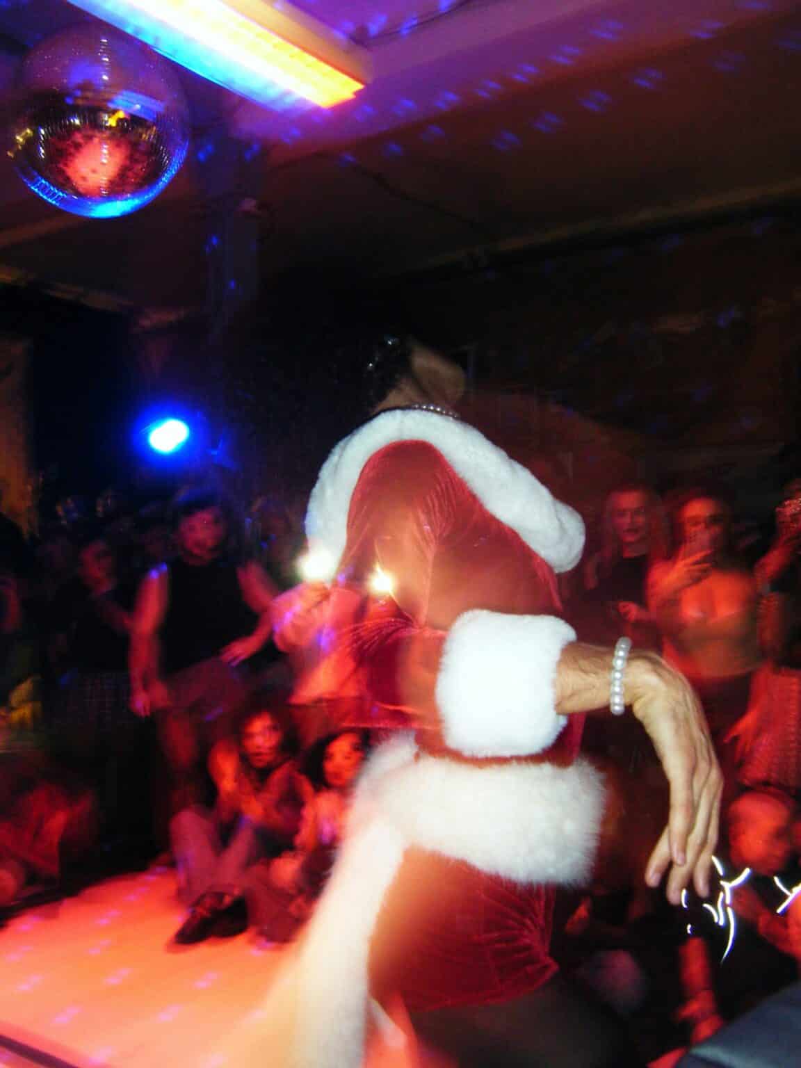DJ sorgt auf einer Weihnachtsfeier mit Tanzfläche und Disco-Kugel für ausgelassene Stimmung.