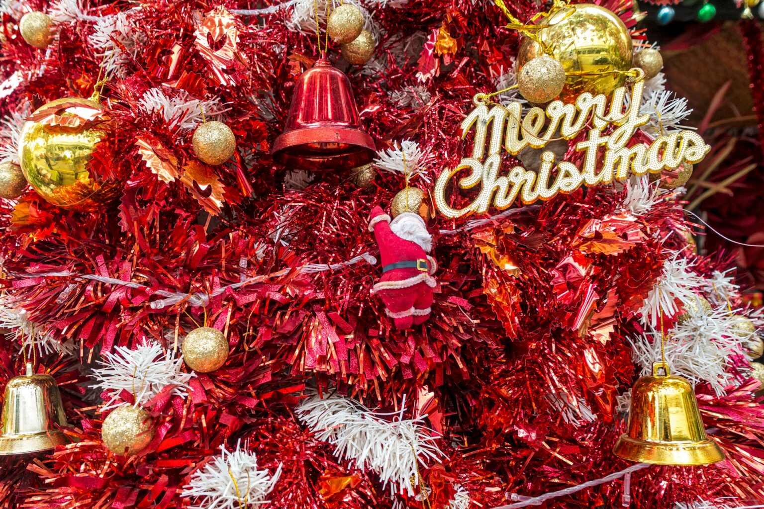 Festlich geschmückter Weihnachtsbaum mit roten und goldenen Christbaumkugeln und Weihnachtsdekoration.
